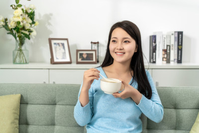 一位年轻女士在家吃早餐喝粥