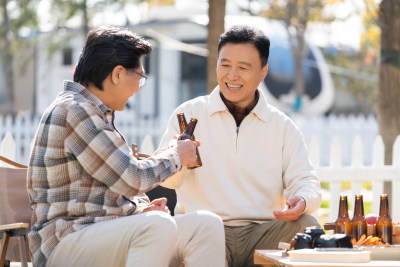 两个老年男人坐在露营地喝啤酒