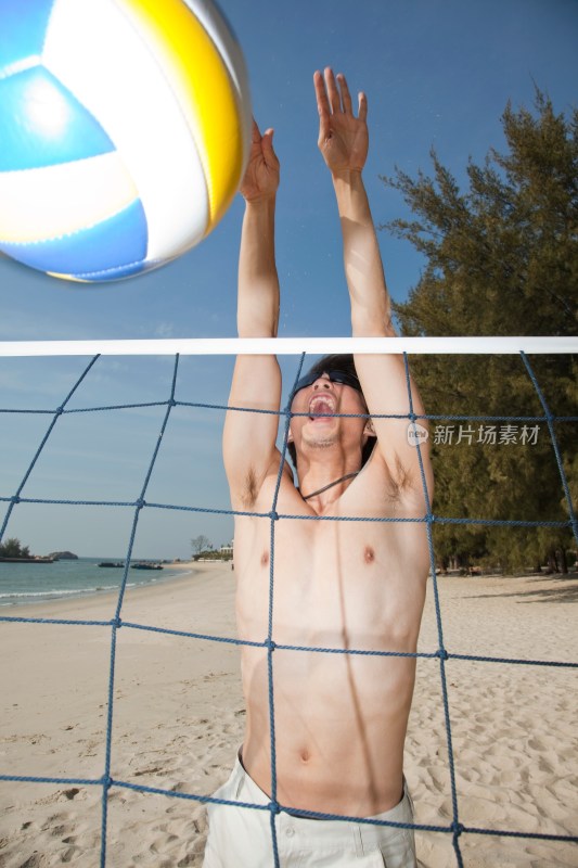 海边年轻男人玩沙滩排球