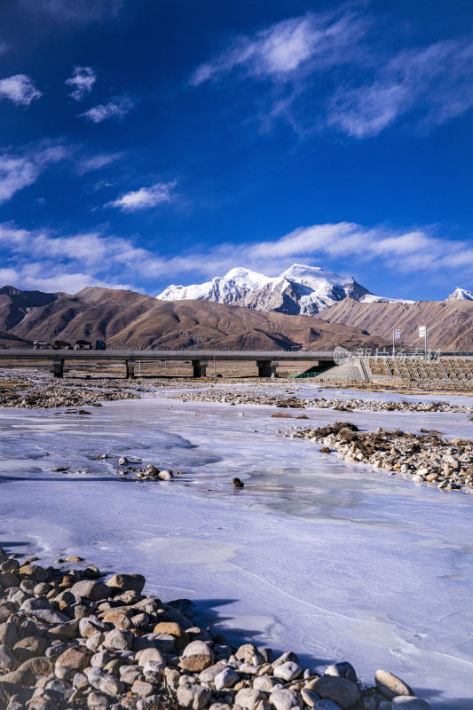 雪山下带桥的结冰河面景观