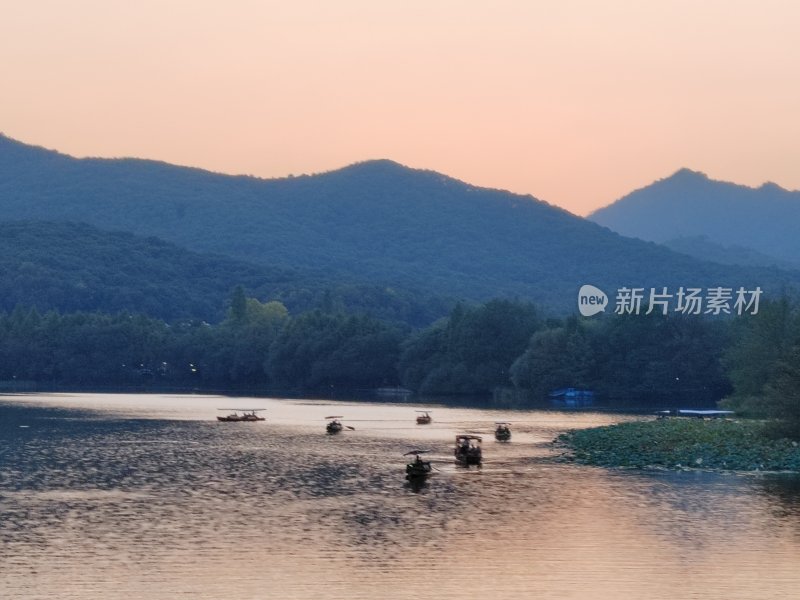 暮色下的湖光山色及湖面小船景象