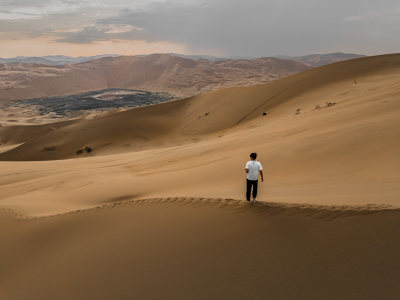 男人拿着相机在沙漠中行走