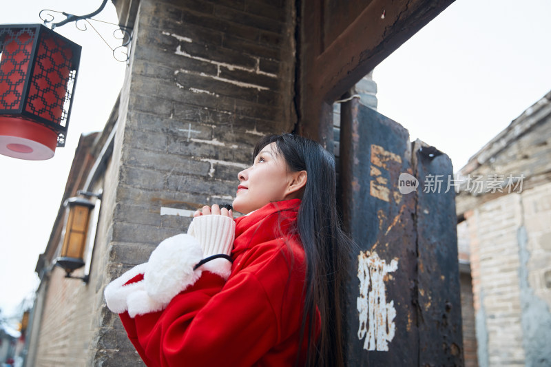 雪后在老城古巷穿着喜庆服饰的亚洲少女