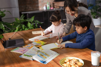 青年女人辅导小学生在家学习