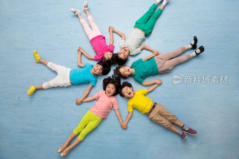 幼儿园儿童躺在地板上手拉手微笑