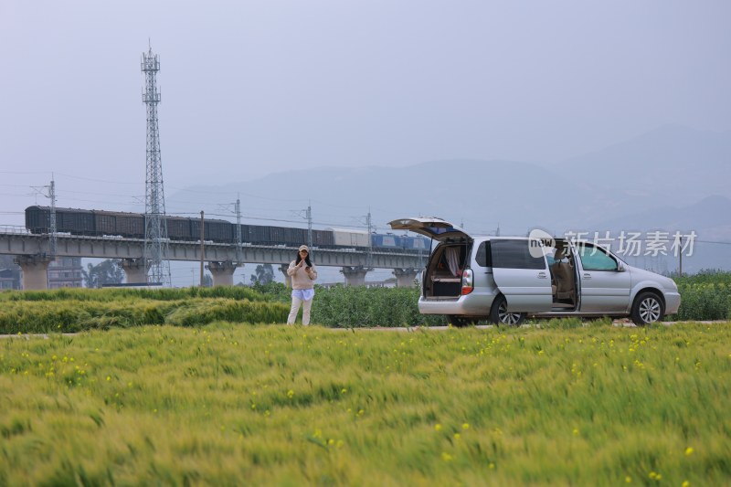 女子在田野旁打开车门站立