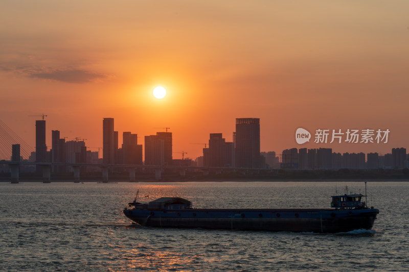 日落时分江面上货船航行的城市景观