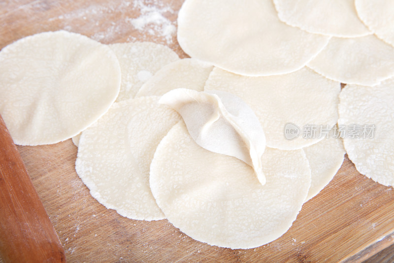 砧板上大量饺子皮和一个包好的饺子