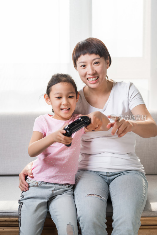 坐在沙发上玩电子游戏的中国母女
