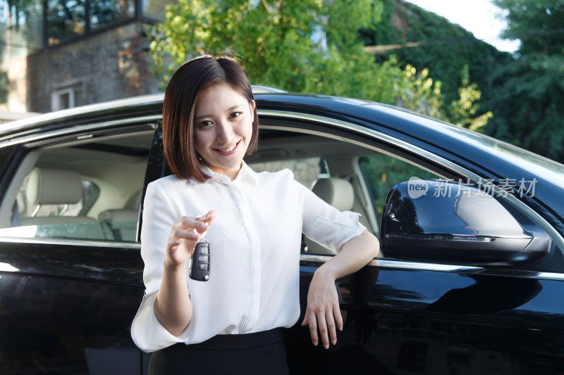 青年女人拿着车钥匙站在汽车旁边