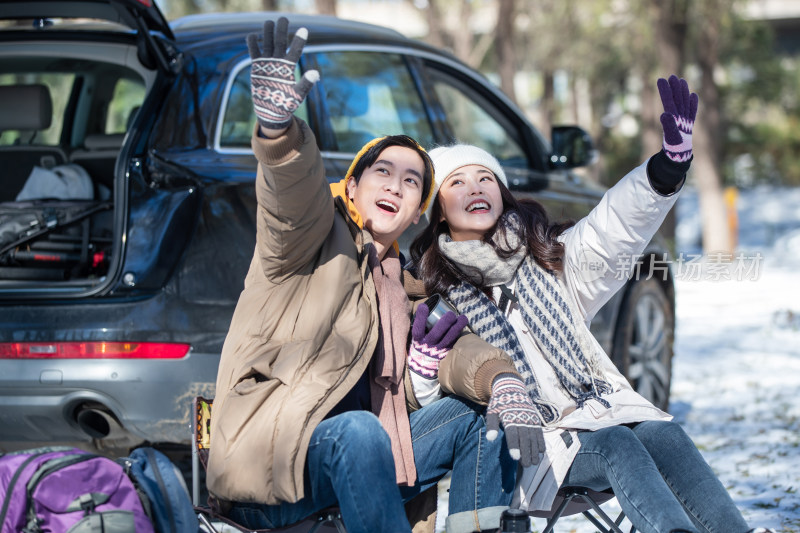 坐在汽车旁的青年夫妇