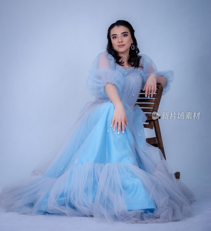 身着蓝纱裙女子坐于木椅