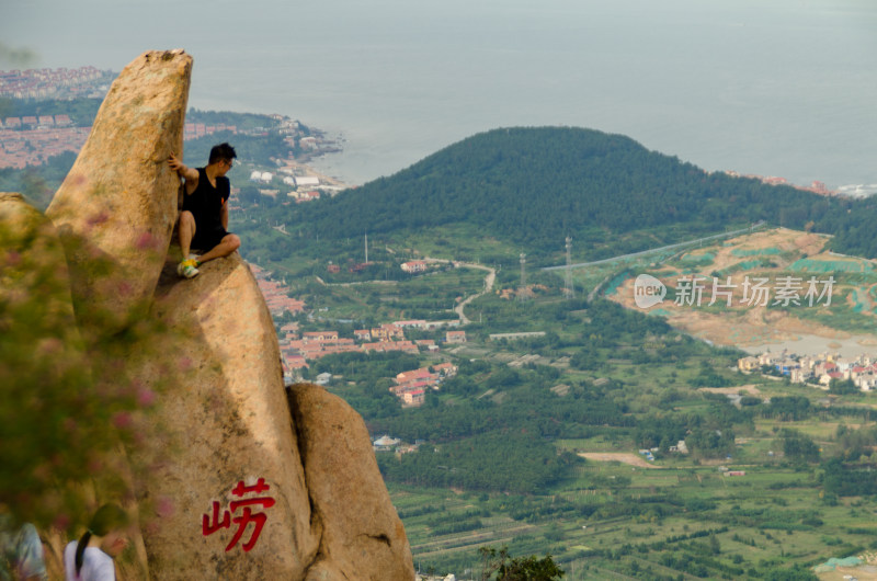 青岛崂山又游客爬上巨石登山看海