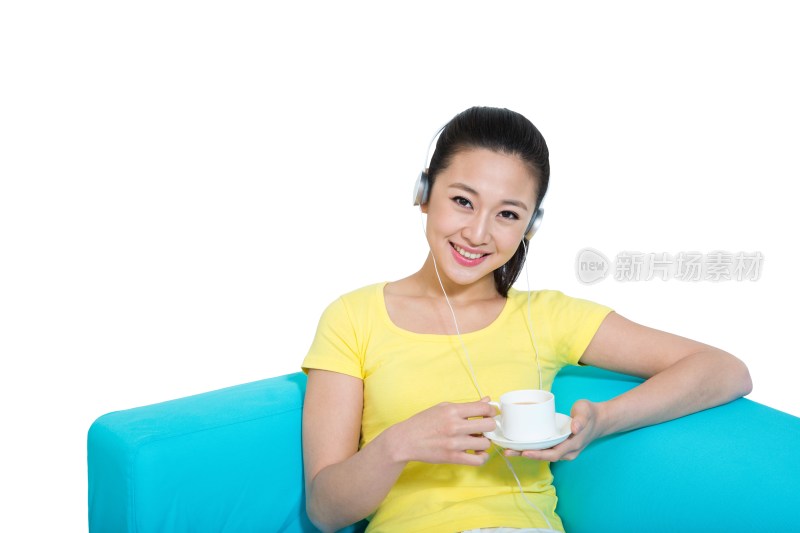 棚拍年轻女人坐在沙发上听着音乐喝咖啡