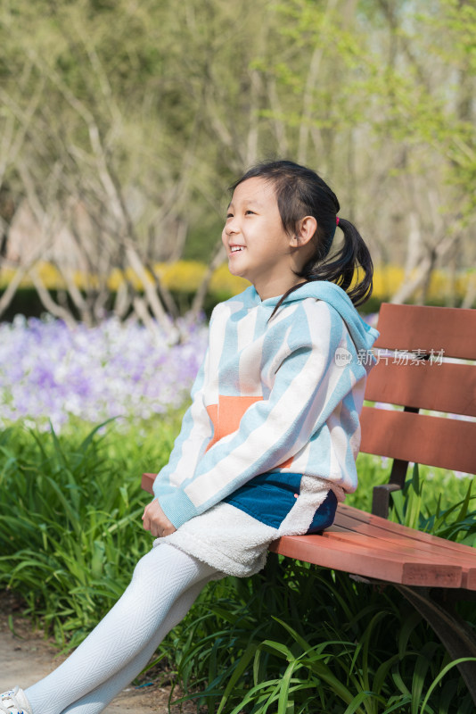 6岁的女孩坐在公园的长椅上