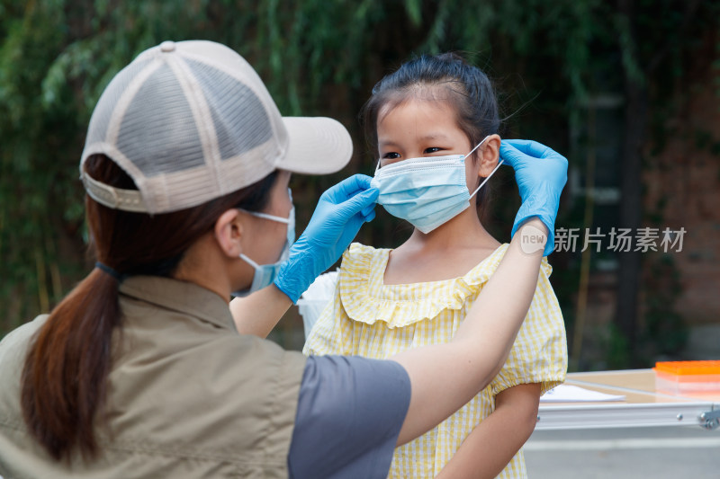 社区志愿者帮小女孩戴口罩