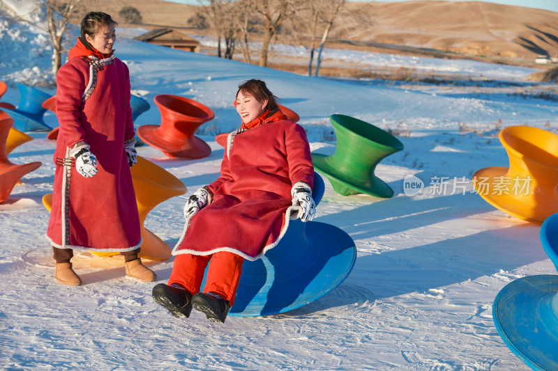 在冰天雪地玩耍雪上娱乐载具车辆的闺蜜少女