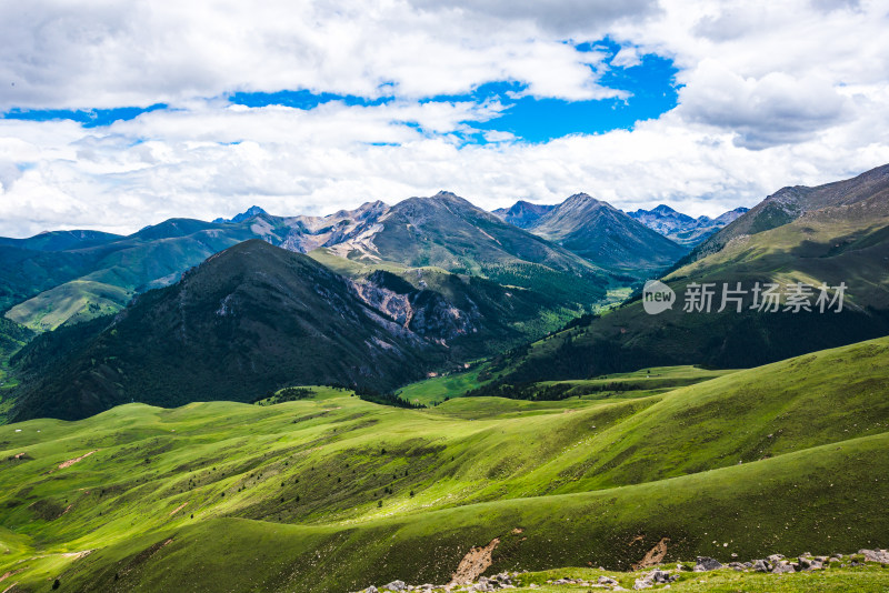 蓝天白云下广袤草原与连绵山峦自然风景