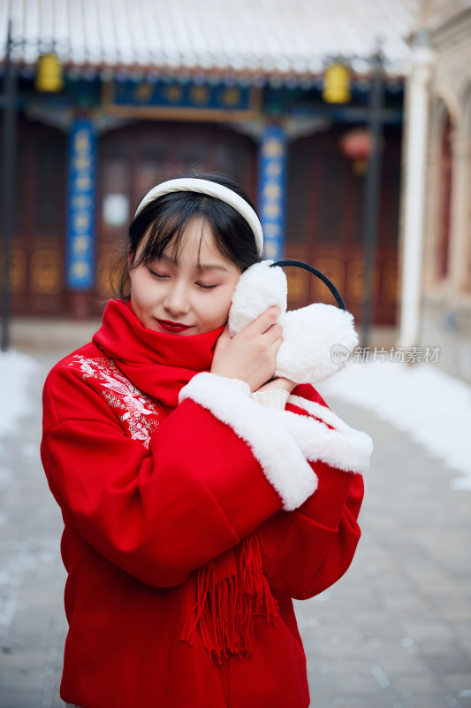 雪后在老城古巷穿着喜庆服饰的亚洲少女