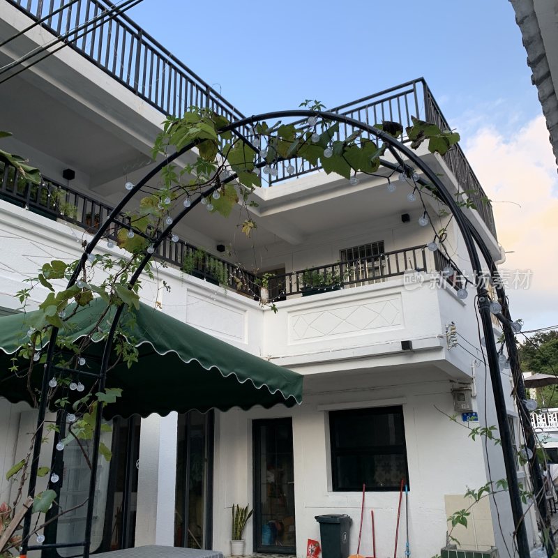 带绿植拱门的白色两层住宅
