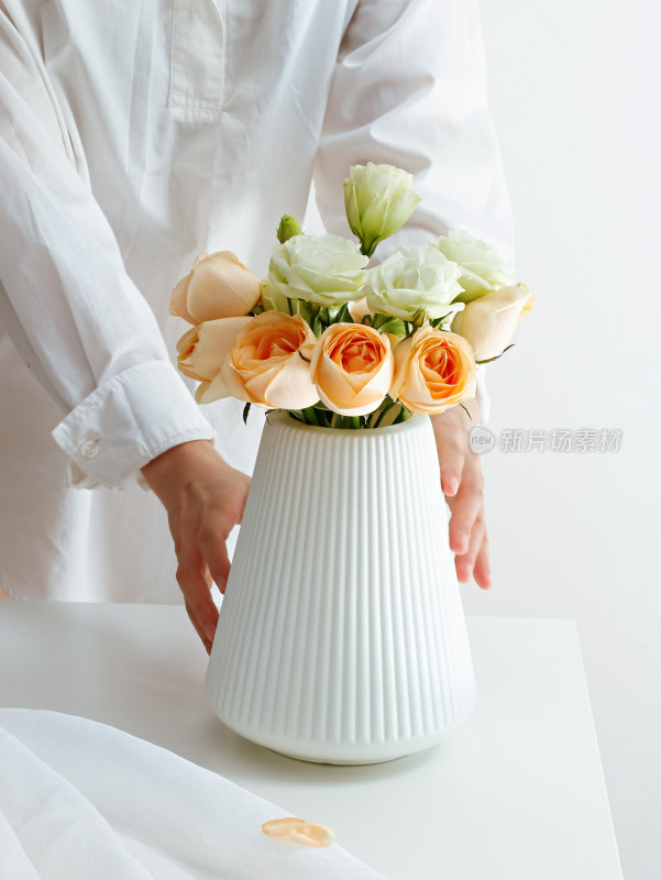 白色桌子上摆放着一束鲜花玫瑰和洋桔梗