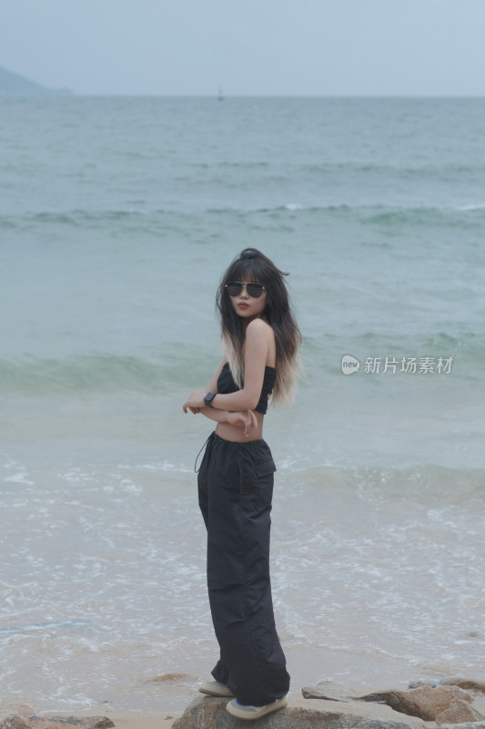 戴墨镜站在海边的长发时尚女孩肖像