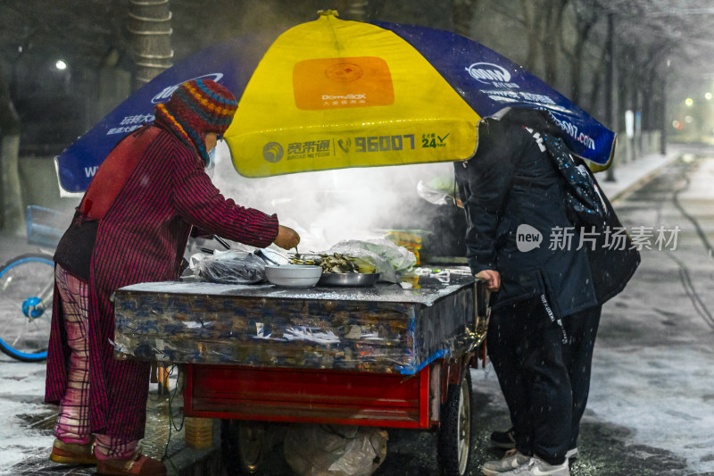 雪夜中街边小吃摊的营业景象