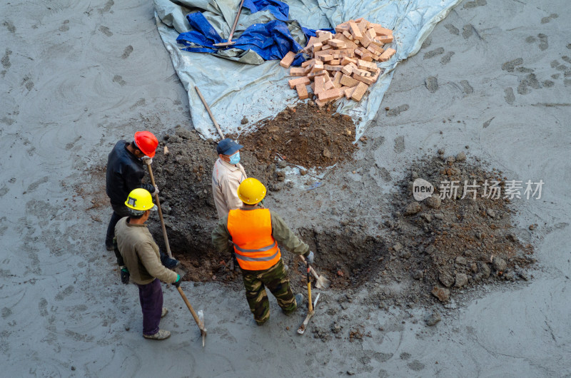 建筑工地上几个合作挖坑的建筑工人