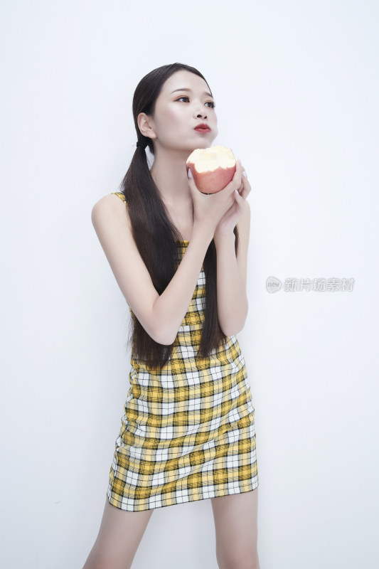 手拿苹果身穿格子吊带裙的亚洲可爱少女人像