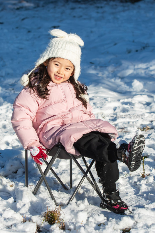 快乐的小女孩坐在雪地上玩耍