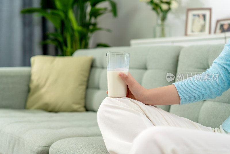 一位年轻女士在沙发上喝牛奶