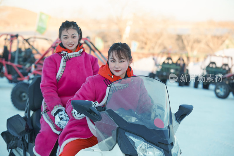 在冰天雪地玩耍雪上娱乐载具车辆的闺蜜少女