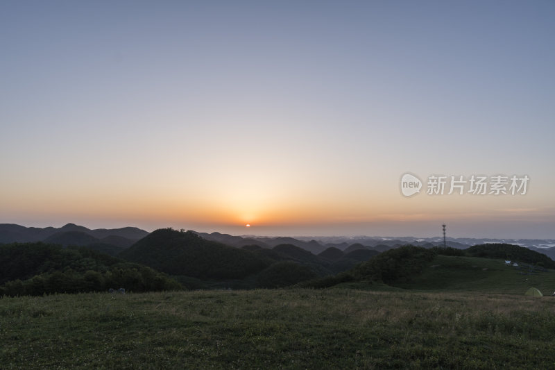 阳光下的广袤草原与起伏山脉的美景