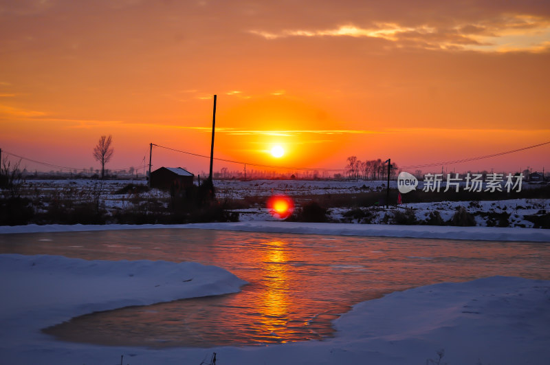 乡村日落美景映照在冰雪覆盖的河面