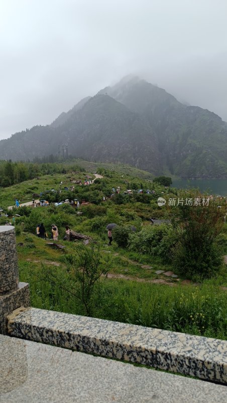 山间草地游客雨中漫步