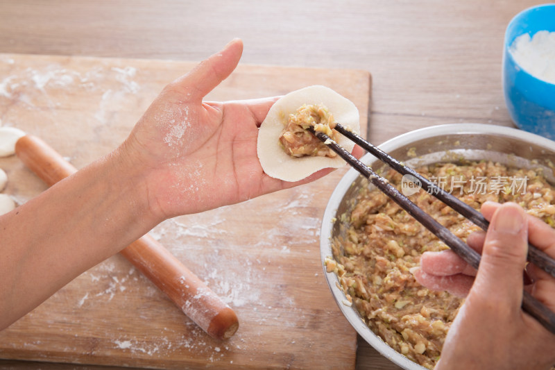 一盆饺子馅上一双手正在包饺子