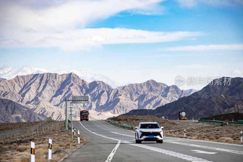 蓝天白云群山背景下的高速公路和行驶的汽车