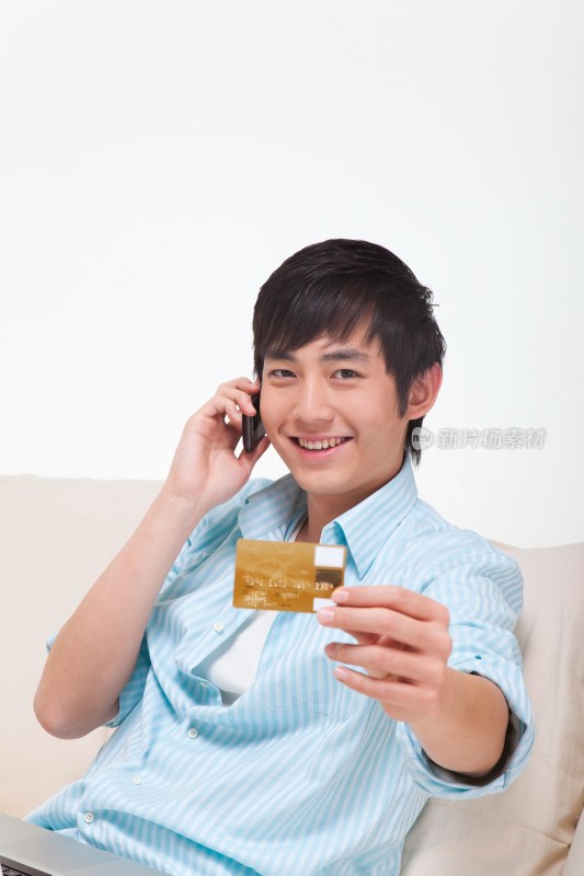 年轻男人拿着银行卡打电话