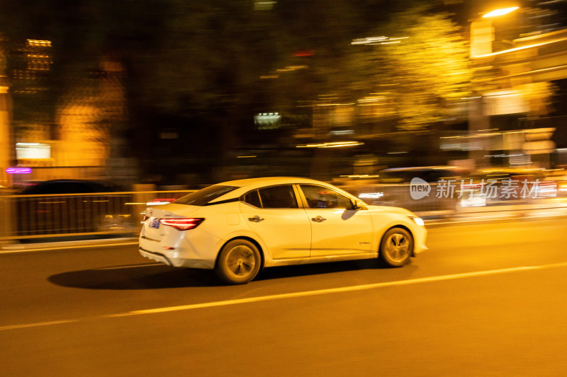 都市夜色中夜幕下的疾驰的白色轿车