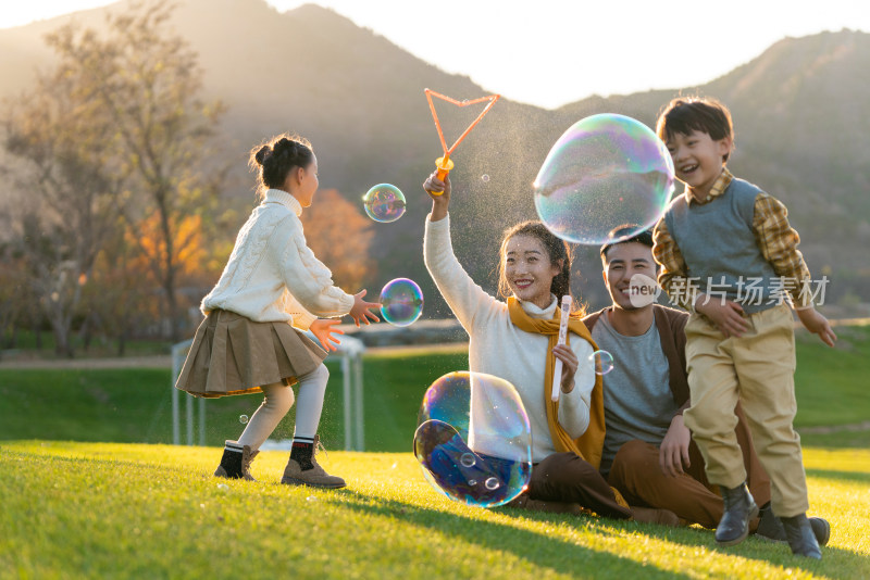 年轻夫妻和孩子们在草地上玩泡泡