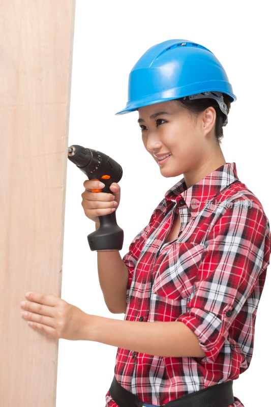 年轻的女建筑工人拿着电钻