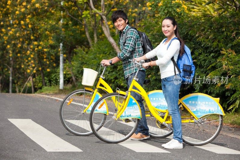 年轻大学生情侣在校园里骑车过马路