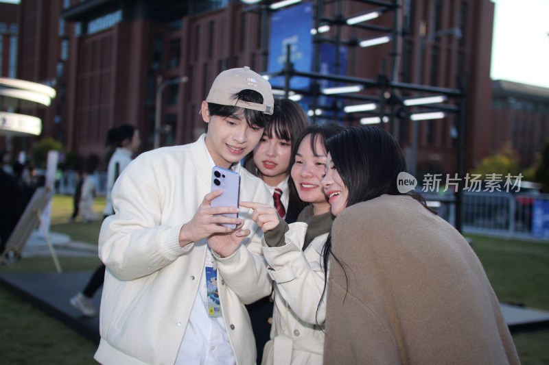 年轻人户外一起看手机画面