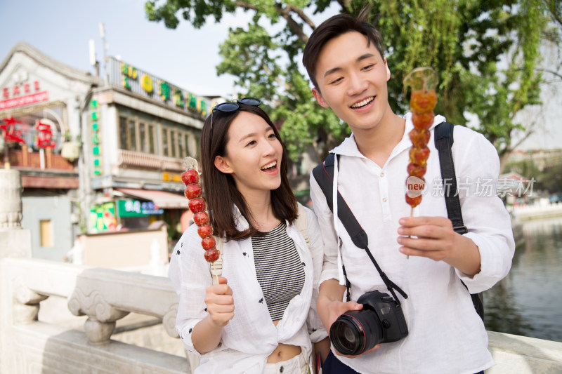 青年情侣旅游拿着糖葫芦