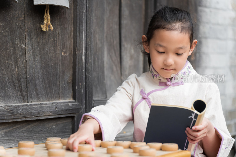 穿中国传统服饰下中国象棋的中国女孩