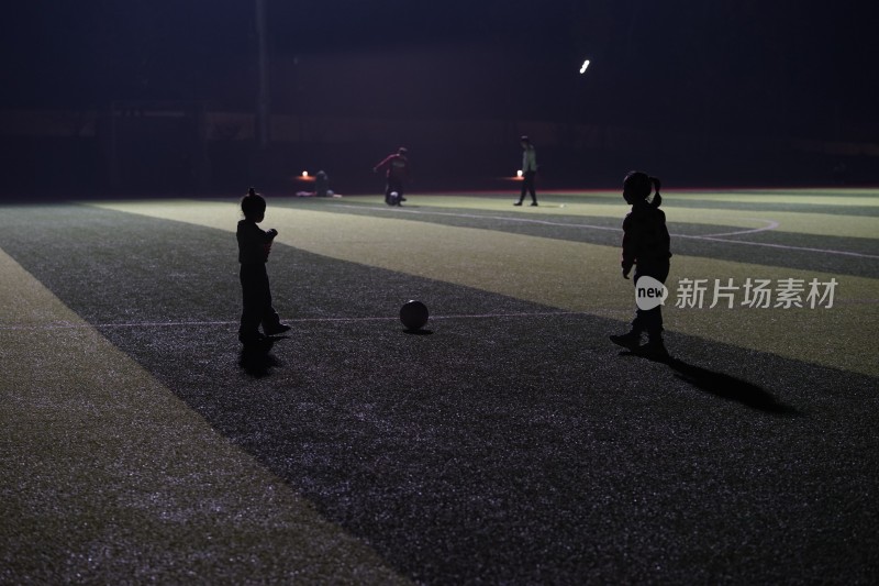 夜晚儿童在足球场踢足球