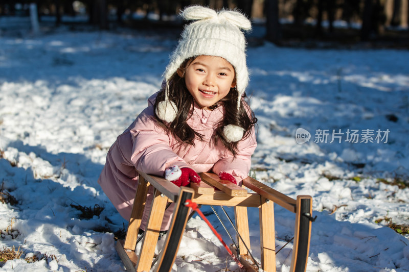 快乐的小女孩在雪地上玩雪橇