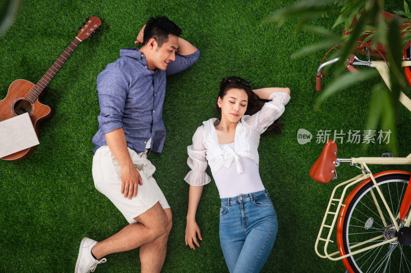 幸福的青年伴侣躺在草地上小憩
