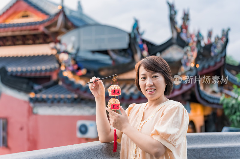 女子手持灯笼站在古建筑旁