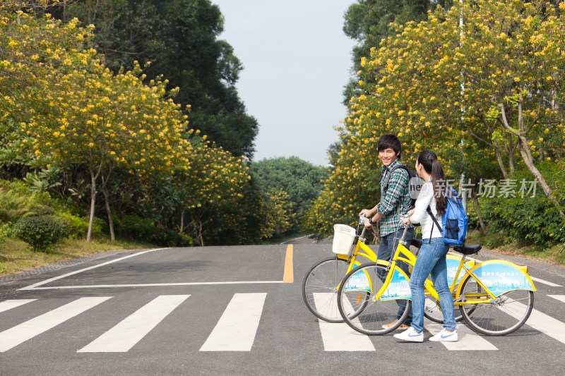 年轻大学生情侣在校园里骑车过马路